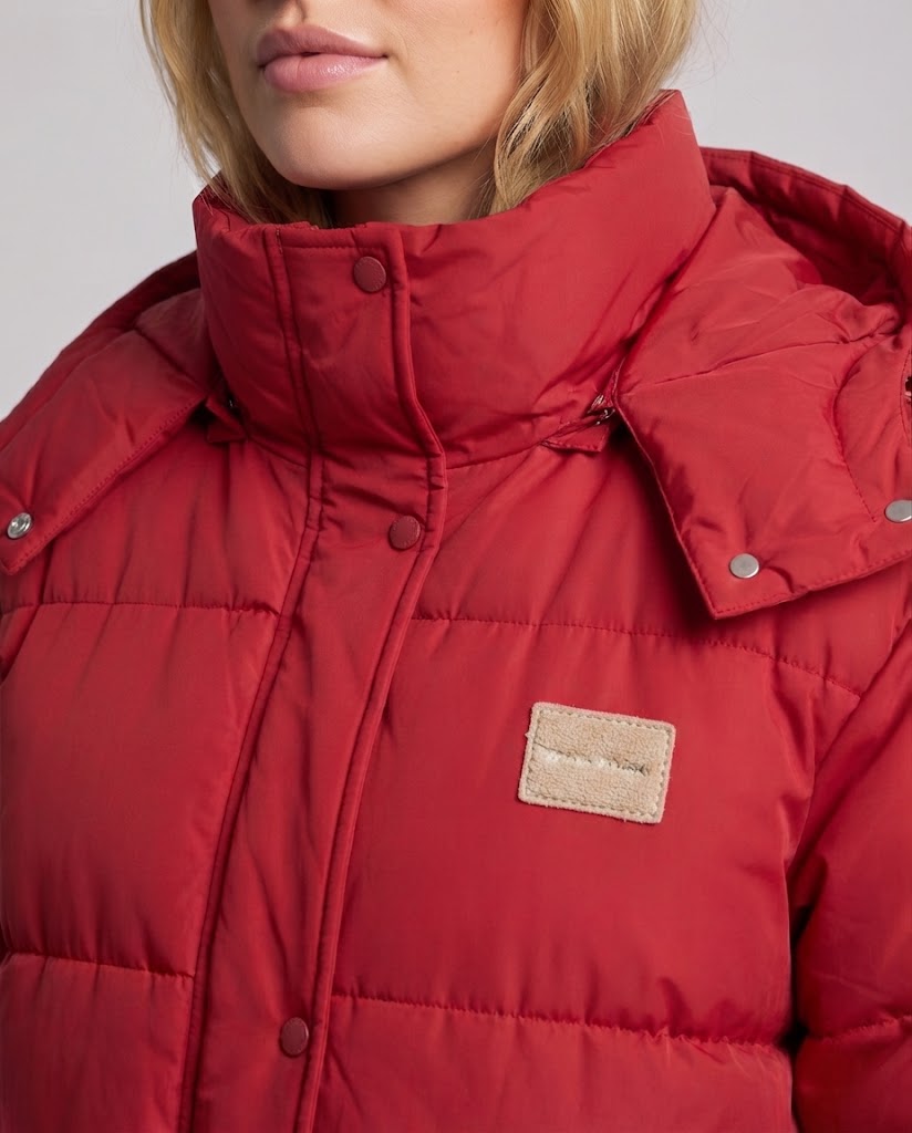 Women's longer quilted thermal coat with contrast stripes on sleeves, high closing collar, and concealed snap button placket